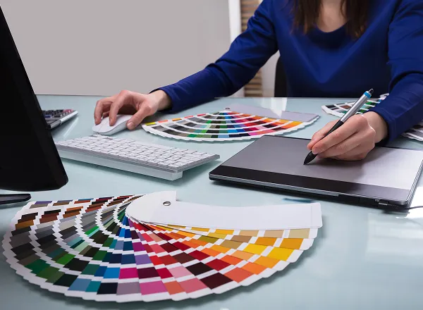 カラーサンプルを見ながら、パソコンで作業している