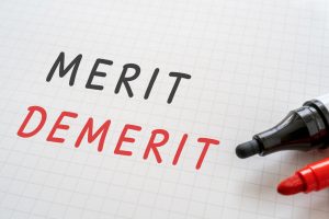 MERIT DEMERITと書かれたノートとマーカー